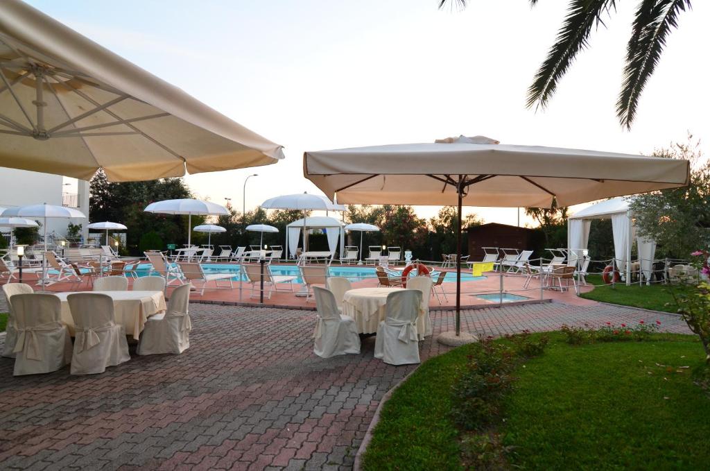 un patio avec tables, chaises et parasols dans l'établissement Hotel Parco degli Ulivi, à Scerne