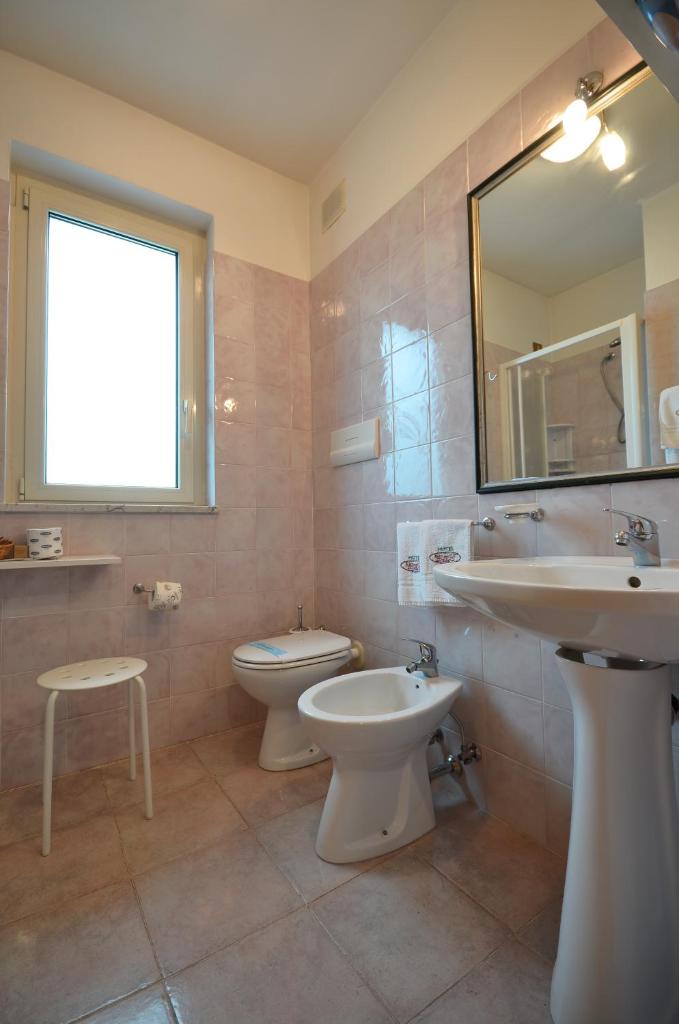 une salle de bain avec un lavabo, des toilettes et un miroir dans l'établissement Hotel Parco degli Ulivi, à Scerne