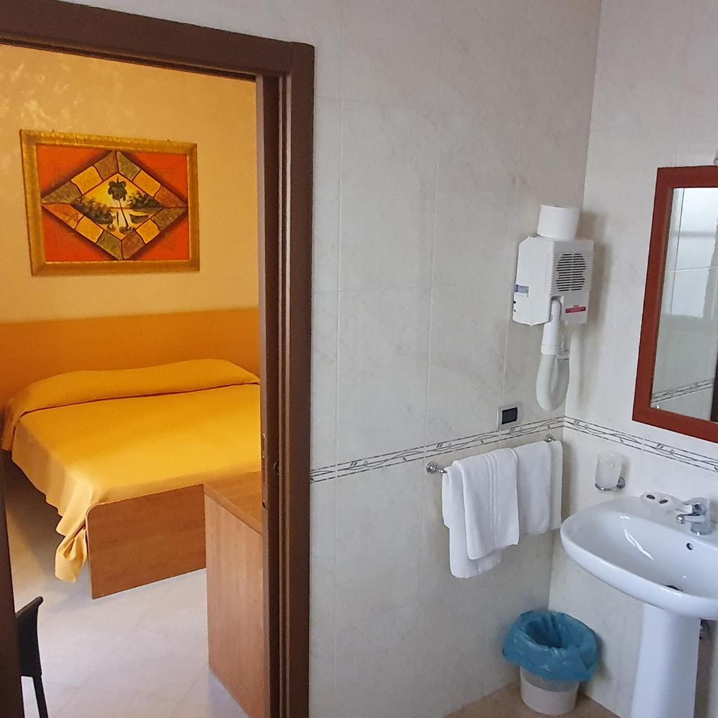 une salle de bain avec un lavabo et une salle de bain avec un lit dans l'établissement Hotel Ristorante Rinelli, à Margherita di Savoia