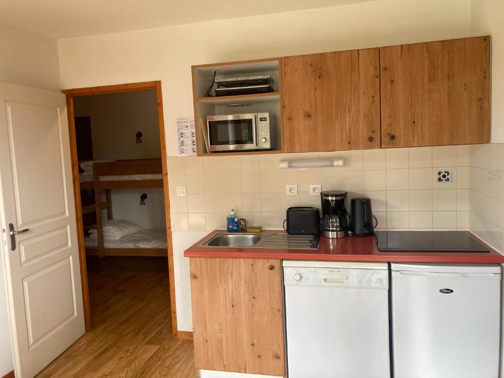 une cuisine avec un évier et un micro-ondes dans l'établissement Appartement pied des pistes, terrasse wifi et parking, à Chamrousse