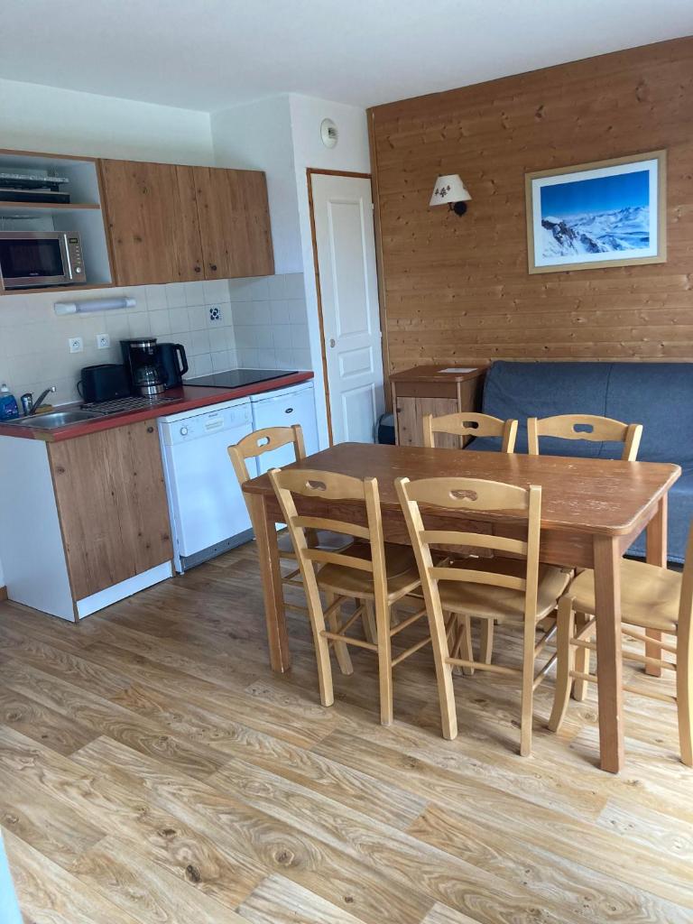 une cuisine et une salle à manger avec une table et des chaises en bois dans l'établissement Appartement pied des pistes, terrasse wifi et parking, à Chamrousse