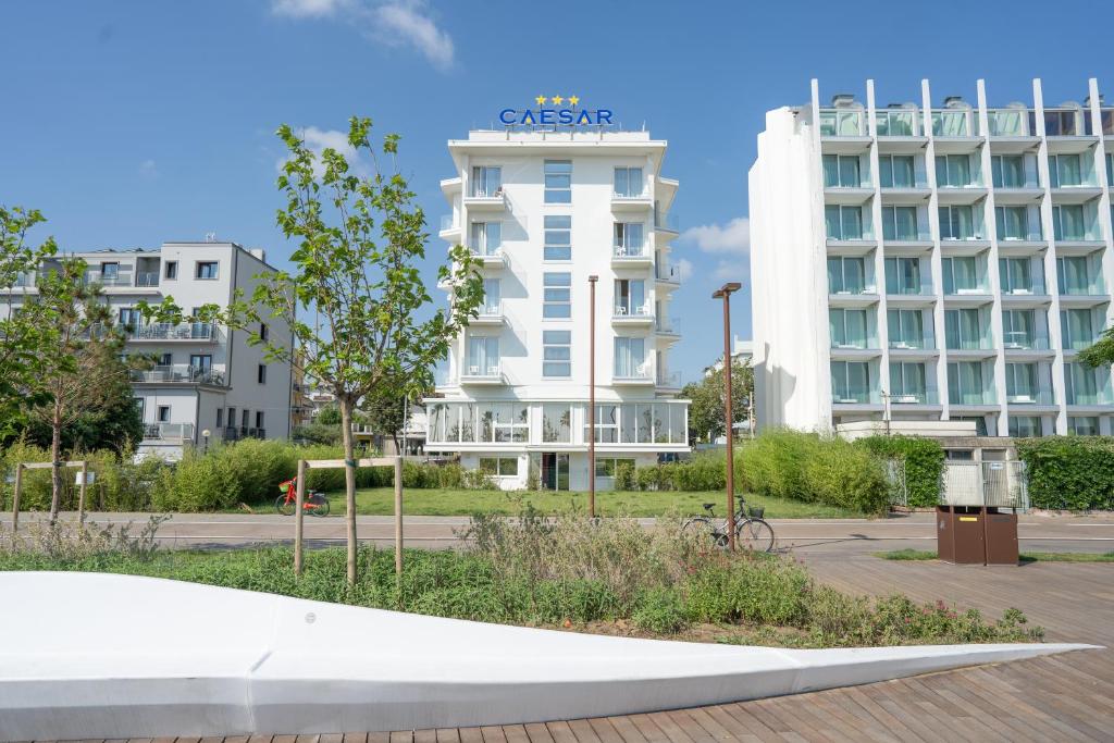 un bâtiment blanc avec une enseigne au sommet dans l'établissement Hotel Caesar, à Rimini