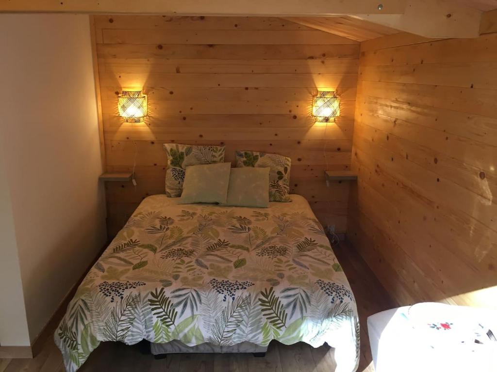 une chambre avec un lit dans un mur en bois dans l'établissement Cabane au milieu des bois, à Lanvellec