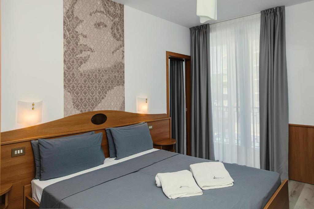 une chambre avec un lit bleu avec deux serviettes dessus dans l'établissement Hotel Leonardo Da Vinci Wellness SPA, à Bibione