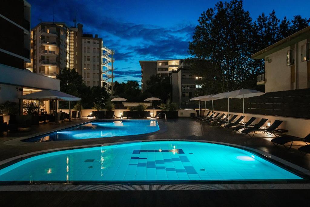 - une piscine avec chaises longues et parasols la nuit dans l'établissement Hotel Leonardo Da Vinci Wellness SPA, à Bibione