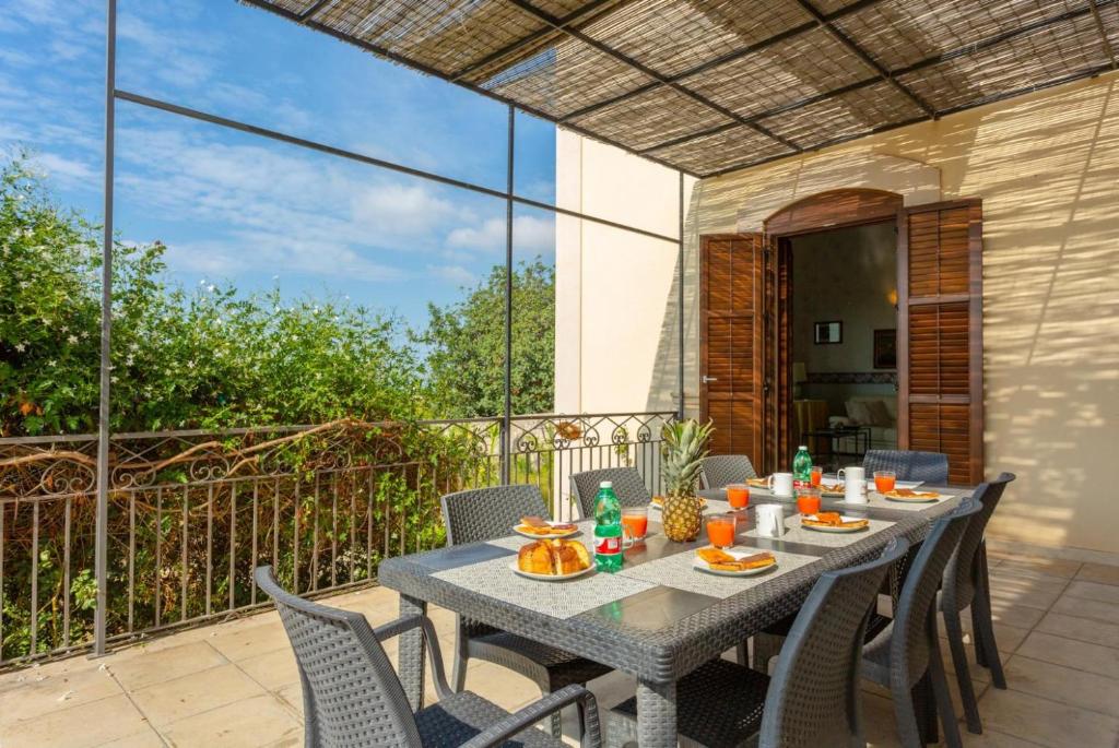 Une table à manger et des chaises sont disponibles sur la terrasse. dans l'établissement Villa Palazzola, à Scicli