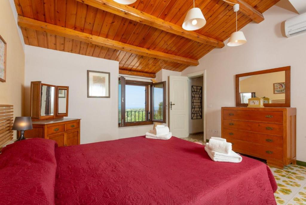 - une chambre avec un grand lit rouge et un plafond en bois dans l'établissement Villa Palazzola, à Scicli