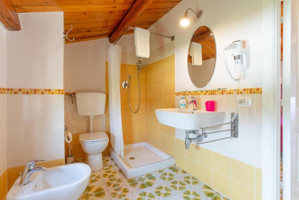 une salle de bain avec un lavabo, des toilettes et un miroir dans l'établissement Villa Palazzola, à Scicli