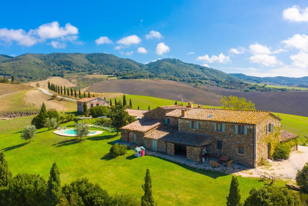 - une vue aérienne sur une grande maison en pierre sur un champ verdoyant dans l'établissement Villa Podere Belvedere, à Sienne