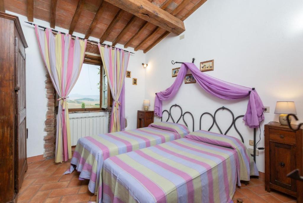 - une chambre dotée d'un lit avec un couvre-lit violet et blanc dans l'établissement Villa Podere Belvedere, à Sienne