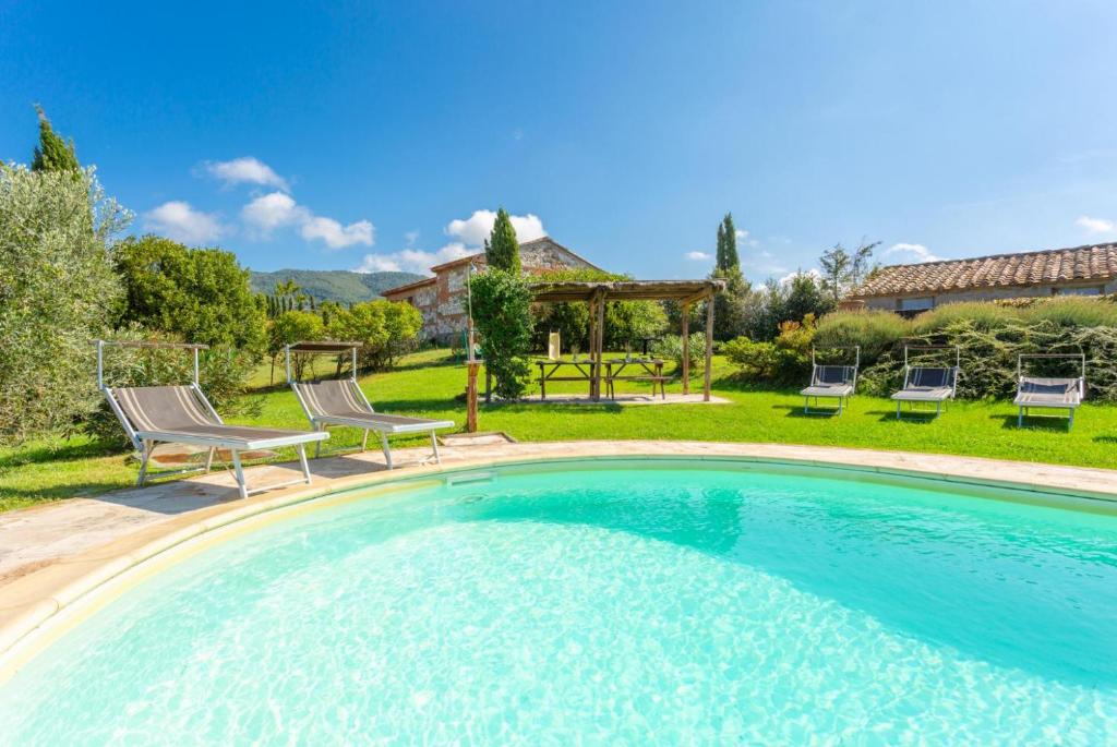 une piscine avec deux chaises et un gazebo dans l'établissement Villa Podere Belvedere, à Sienne