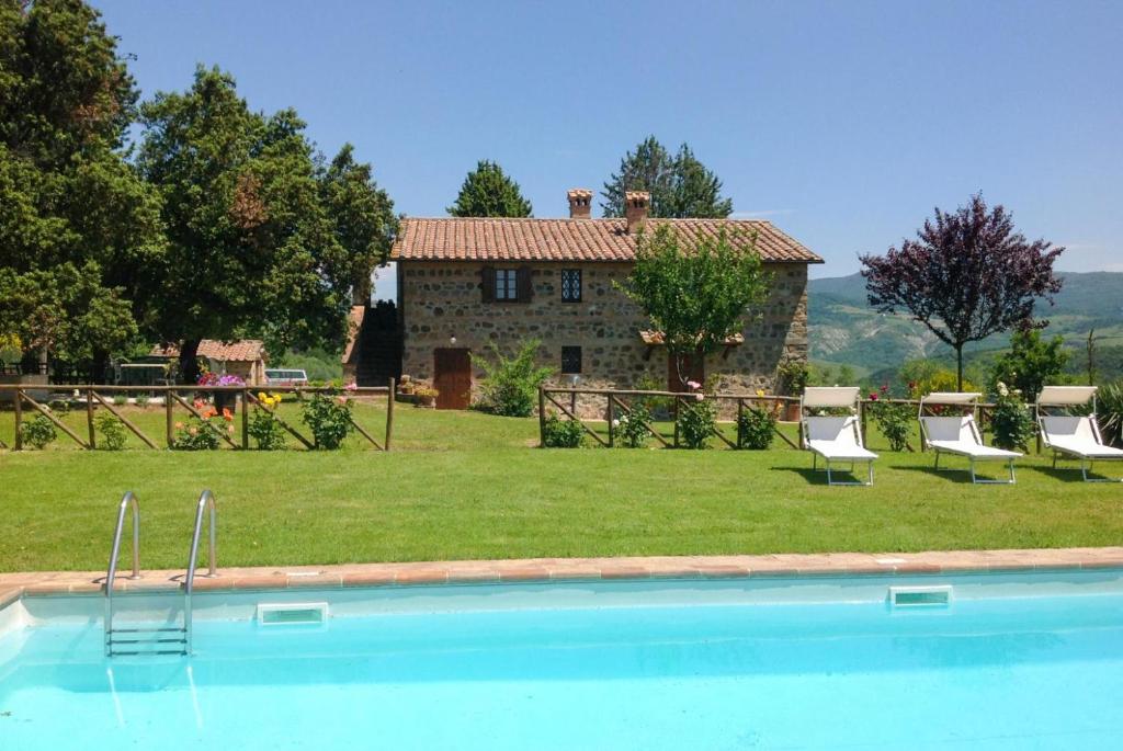 - une piscine en face d'une maison en pierre dans l'établissement Casale Donatelli, à Radicofani