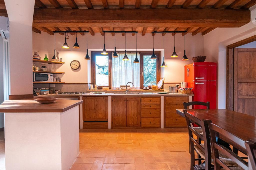 Il comprend une cuisine équipée d'un réfrigérateur rouge et d'une table. dans l'établissement Villa il Melograno, à Parrano