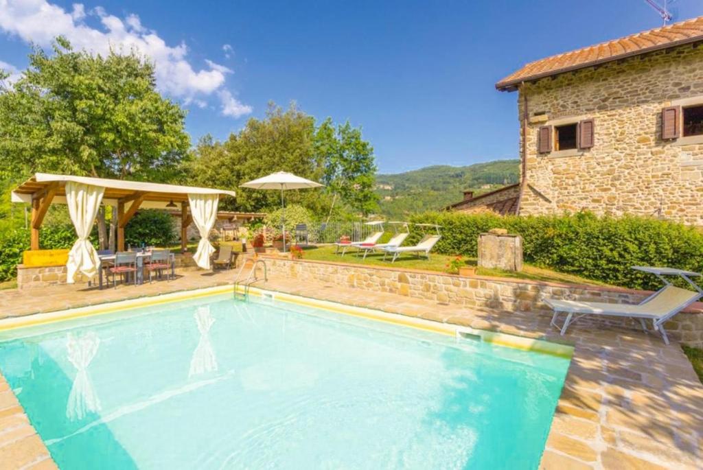une piscine devant une maison dans l'établissement Villa Il Castello, à Ortignano Raggiolo