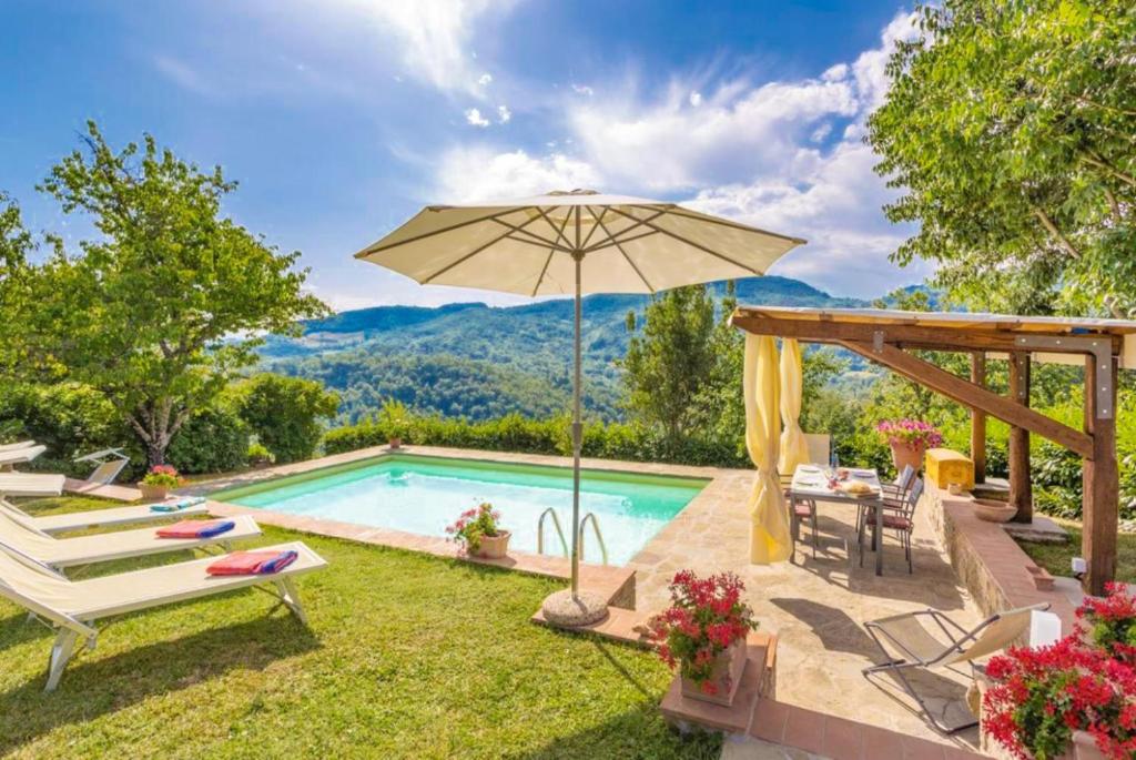 une piscine avec un parasol, une table et des chaises dans l'établissement Villa Il Castello, à Ortignano Raggiolo