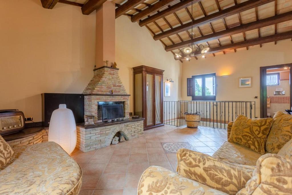 - un salon avec une cheminée en pierre et des canapés dans l'établissement Villa Aziz, à Scicli