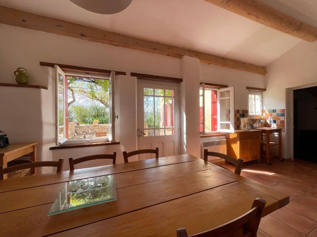 d'une salle à manger avec une table en bois et des fenêtres. dans l'établissement Gîte Roses, à Saint-André-de-Roquepertuis