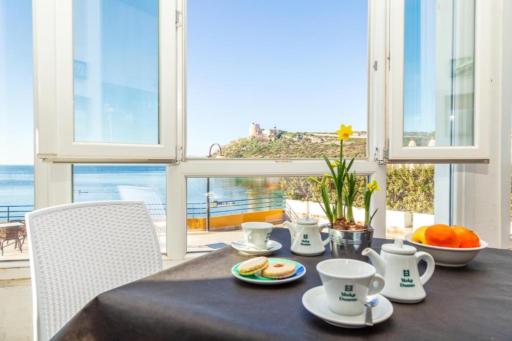 une table avec des tasses et des assiettes de nourriture dans l'établissement Hotel Calamosca, à Cagliari