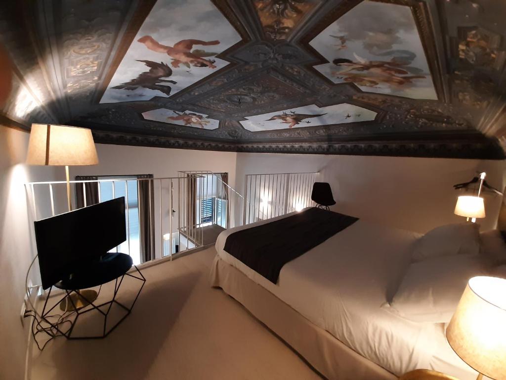 une chambre avec un lit et un plafond orné de tableaux dans l'établissement Hotel Palazzo Vannoni, à Levanto