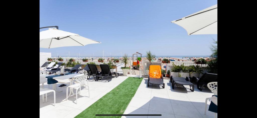 un patio avec tables et chaises sur un toit dans l'établissement Riviera Mare Beach Life Hotel, à Rimini