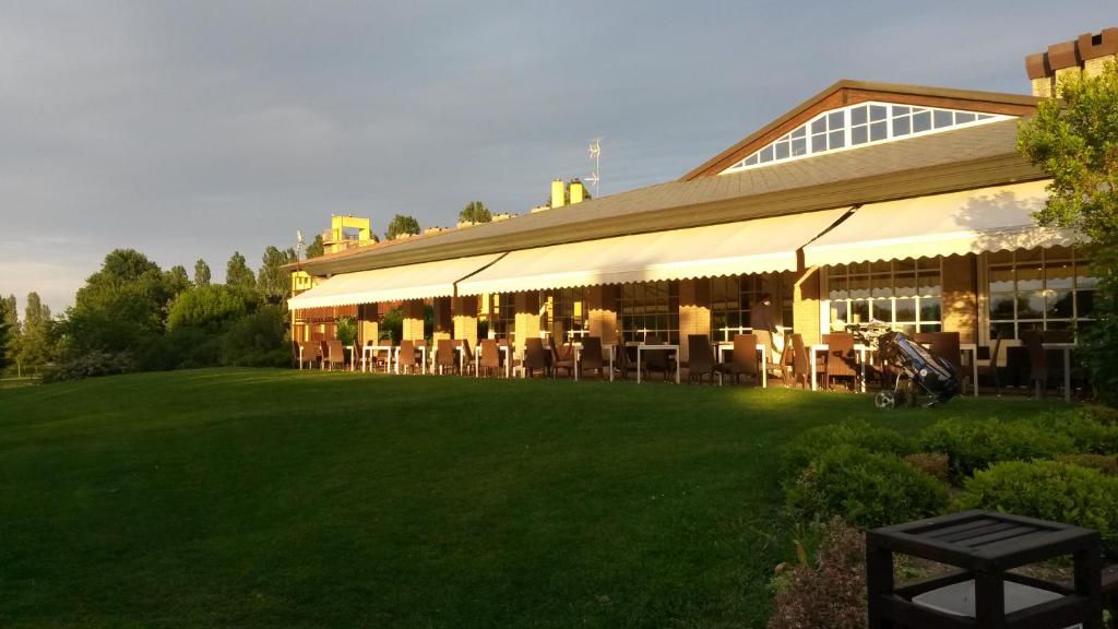 un grand bâtiment avec des tables et des chaises devant dans l'établissement Hotel Golf Inn, à Lignano Sabbiadoro