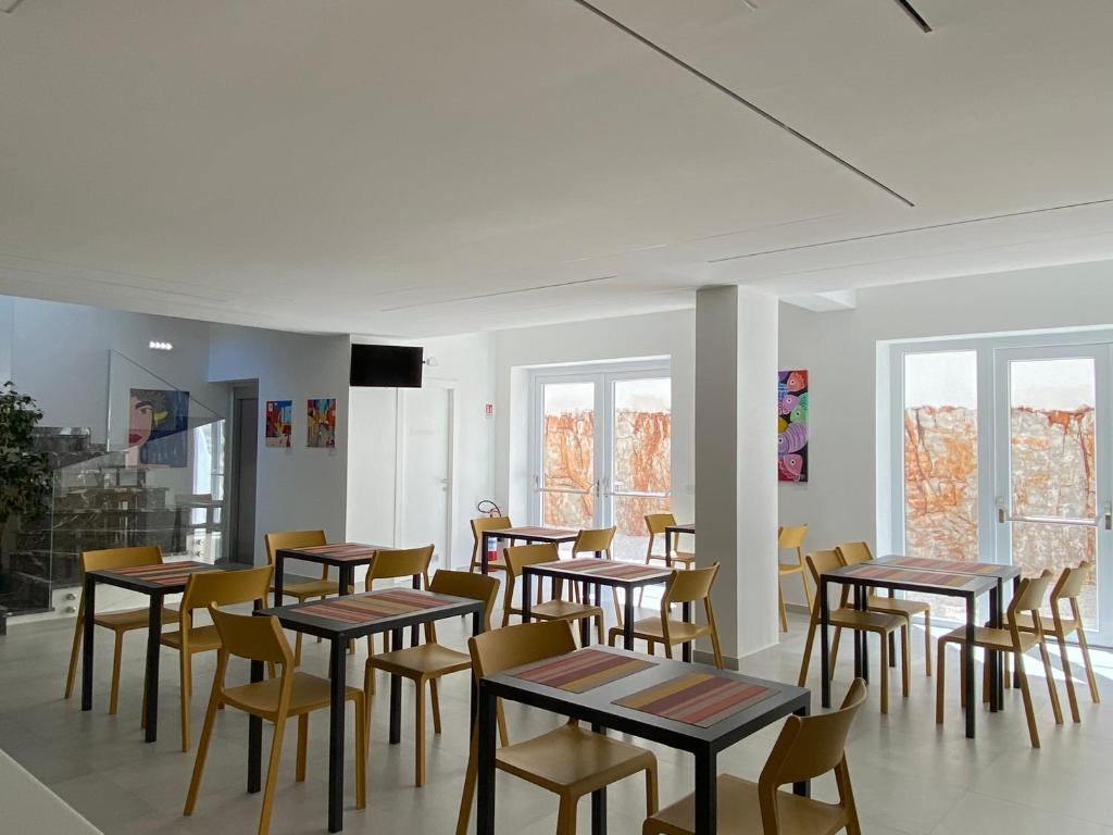 une salle à manger avec tables, chaises et fenêtres dans l'établissement Hotel Arte Mare, à San Vito Lo Capo