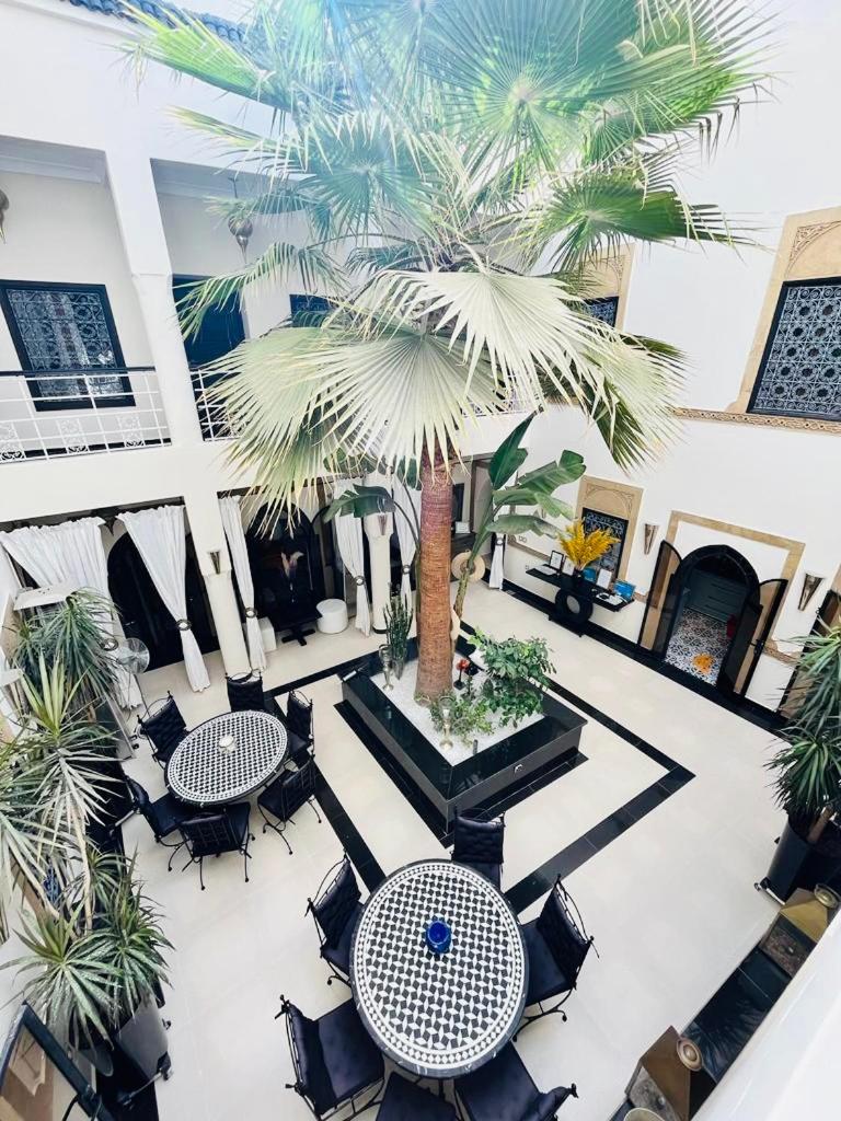 une cour avec des tables, des chaises et un palmier dans l'établissement Riad Oasissime, à Marrakech