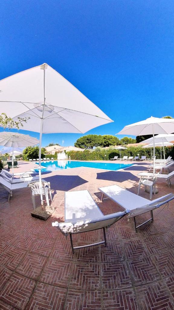 - une piscine avec 2 chaises longues et des parasols dans l'établissement Villa Teti - Sicilia, à Campofelice di Roccella