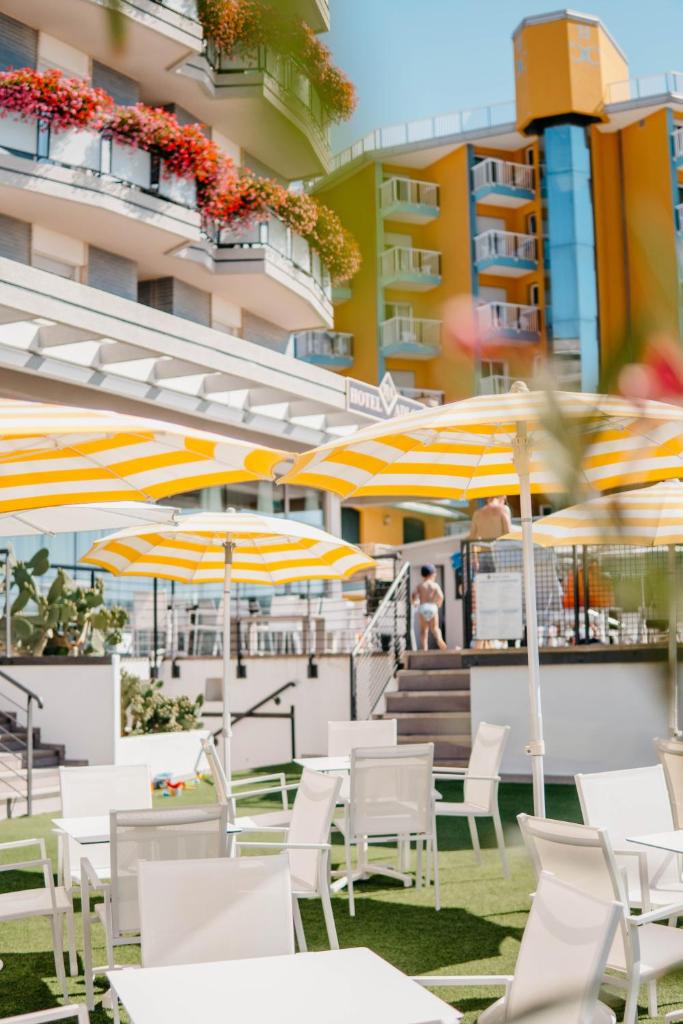 un groupe de tables et de chaises blanches avec parasols dans l'établissement Hotel Adlon, à Lido di Jesolo
