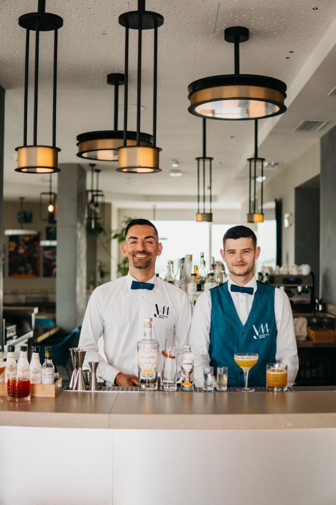 deux hommes se tiennent derrière un bar dans un restaurant dans l'établissement J44 Lifestyle Hotel, à Lido di Jesolo 127 autres photos