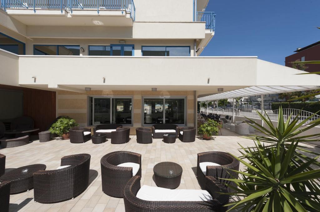 un patio avec des chaises et des tables devant un bâtiment dans l'établissement Hotel Miami, à Lido di Jesolo