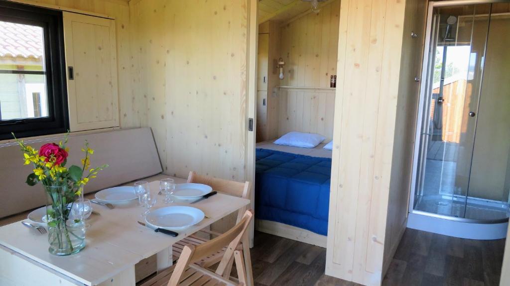 Cette petite chambre comprend une table et un lit. dans l'établissement Lodges du Ushuaïa Villages Camping les 4 Saisons, à Grane