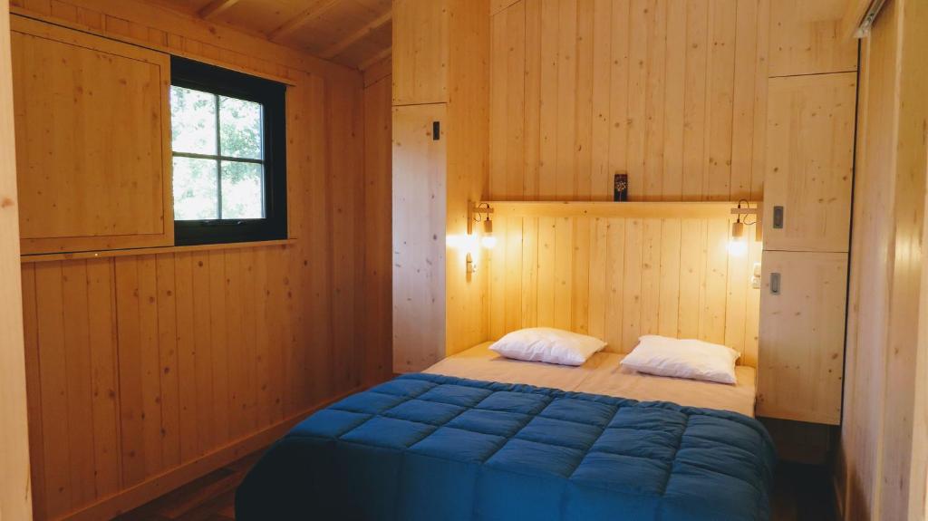 une chambre avec un lit dans une pièce en bois dans l'établissement Lodges du Ushuaïa Villages Camping les 4 Saisons, à Grane