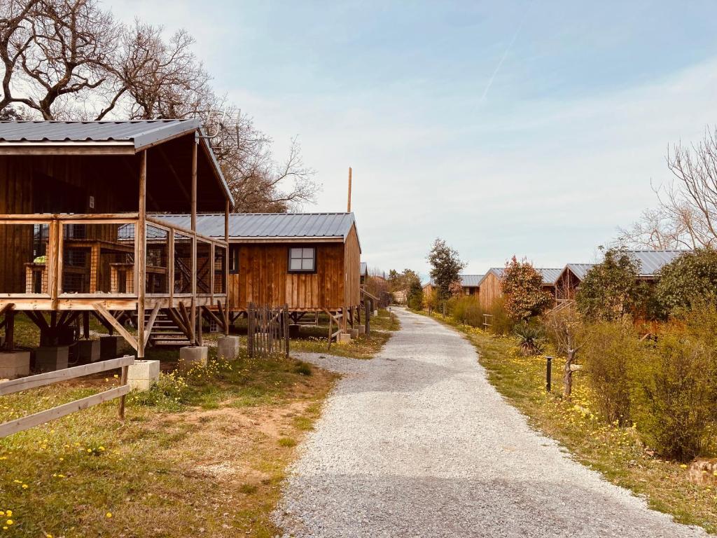 un chemin de terre à côté d'une maison en bois dans l'établissement Lodges du Ushuaïa Villages Camping les 4 Saisons, à Grane