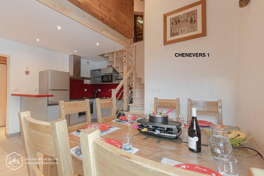 une cuisine et une salle à manger avec une table et des chaises dans l'établissement LES CHENEVERS, à Lanslevillard
