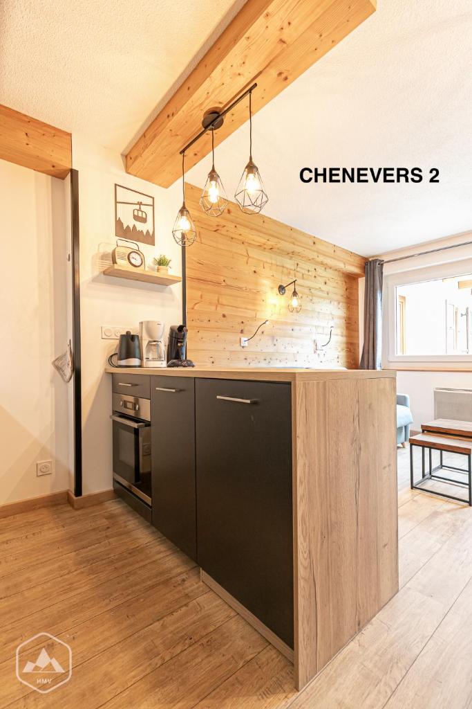 Il comprend une cuisine avec un réfrigérateur noir et des murs en bois. dans l'établissement LES CHENEVERS, à Lanslevillard
