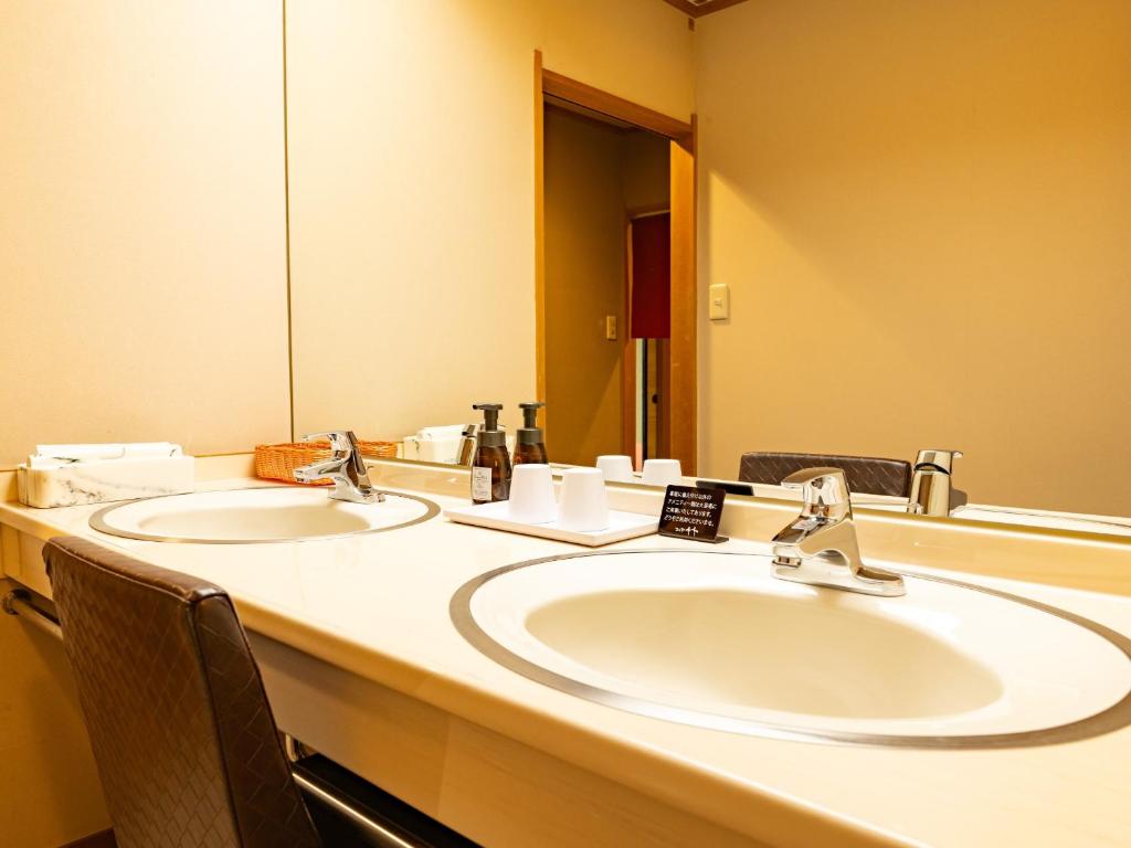 une salle de bain avec deux lavabos et un grand miroir dans l'établissement Awara Onsen Matuya Sen Sen, à Awara