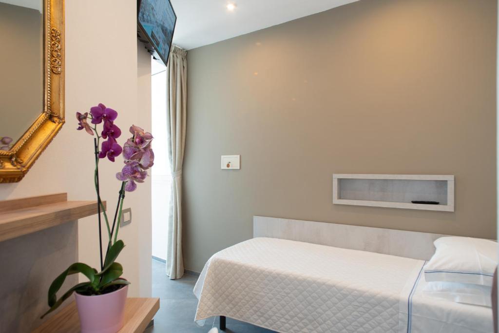 une chambre avec un lit et un vase de fleurs violettes dans l'établissement Hotel Colorado Cesenatico, à Cesenatico