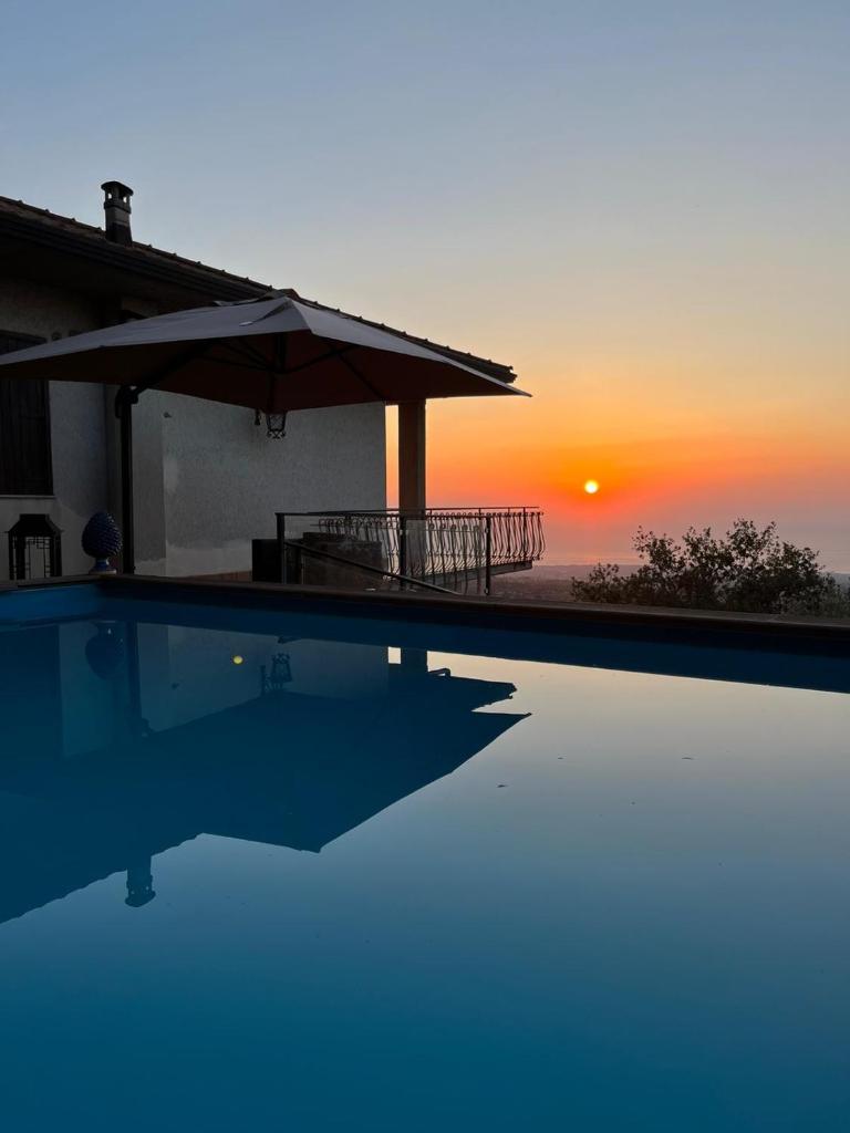 une piscine avec un coucher de soleil en arrière-plan dans l'établissement Villa Maria, à Zafferana Etnea