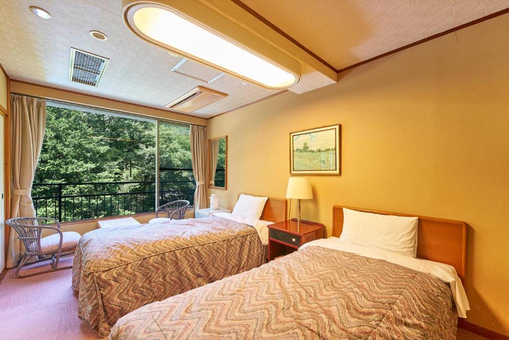 une chambre d'hôtel avec deux lits et une fenêtre dans l'établissement Hakone Yumoto hotel, à Hakone
