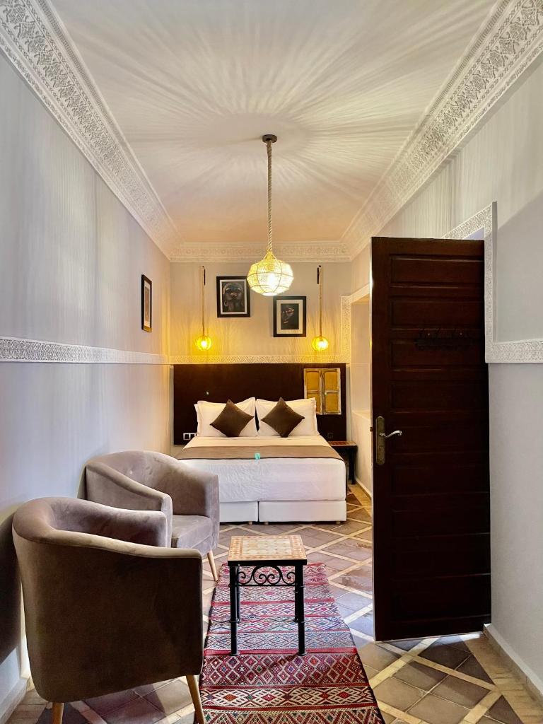 - une chambre avec un lit, deux chaises et une porte dans l'établissement Riad Al Wafaa, à Marrakech