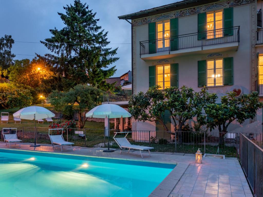 une piscine avec chaises et parasols devant un immeuble dans l'établissement Villa Savio by Interhome, à La Morra