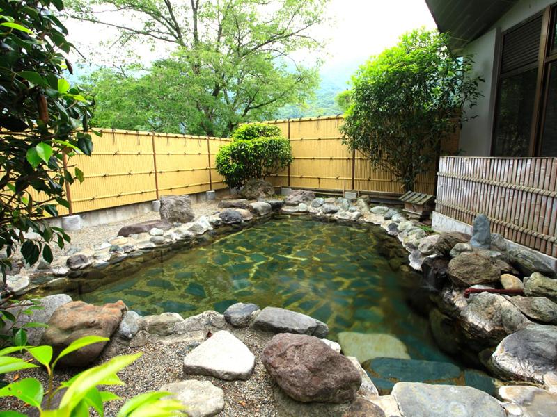 une piscine d'eau avec des rochers devant une maison dans l'établissement Ashinomaki Prince Hotel, à Aizuwakamatsu