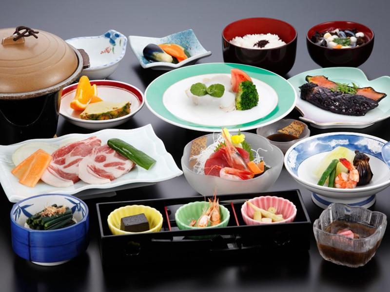 une table recouverte de assiettes et de bols de nourriture dans l'établissement Ashinomaki Prince Hotel, à Aizuwakamatsu