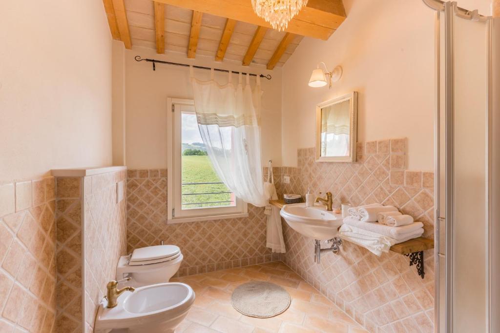 une salle de bain avec deux lavabos et un WC et une fenêtre dans l'établissement Villa del Cucco, à Fossombrone
