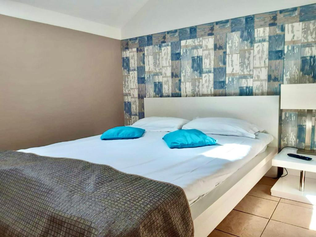 une chambre avec un lit avec des oreillers bleus dessus dans l'établissement Adonis Valberg, à Valberg