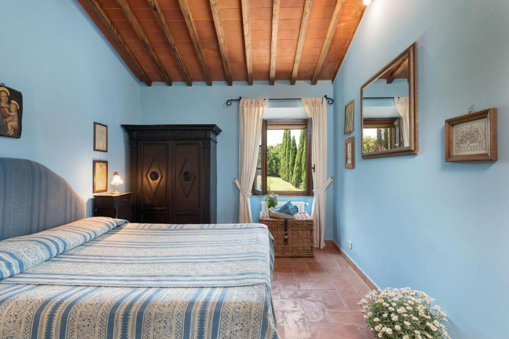 - une chambre avec des murs bleus, un lit et un miroir dans l'établissement Podere Le Pozze, à Sinalunga