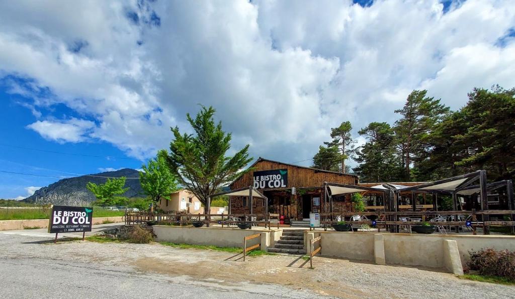 un bâtiment avec des tables et des parasols devant lui dans l'établissement Camping Les Sirènes, à Castellane