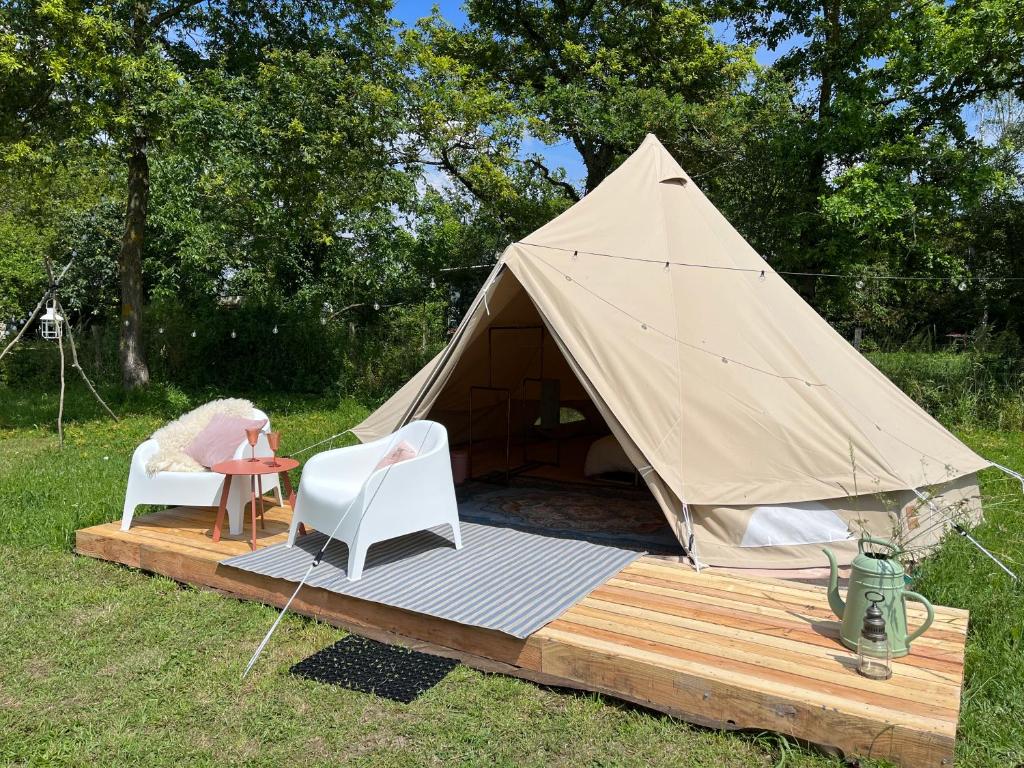 une tente avec une table et des chaises sur une terrasse en bois dans l'établissement Le Brasseur Logements - Tents, à Saint-Caprais 10 autres photos