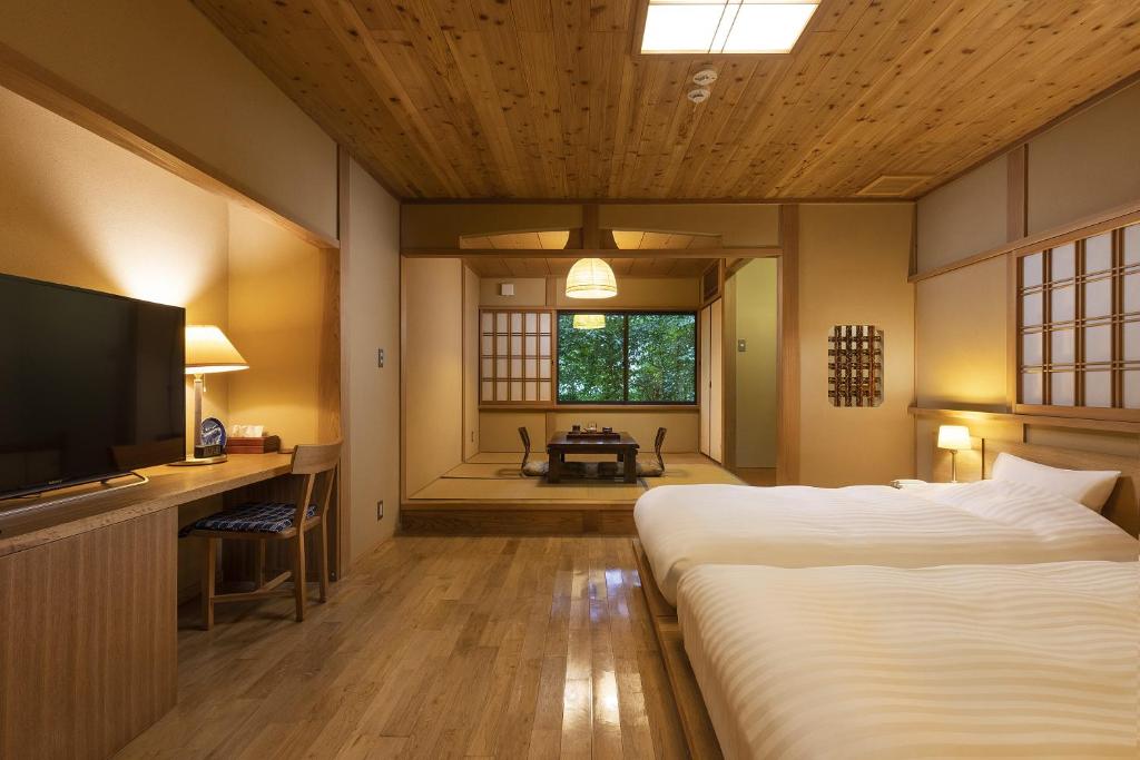 une chambre avec un grand lit et une télévision dans l'établissement Yufuin Yufusaryo, à Yufu